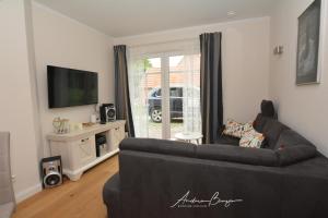 ein Wohnzimmer mit einem schwarzen Sofa und einem TV in der Unterkunft Pension Lütje Huske Zimmer 1 in Südbrookmerland