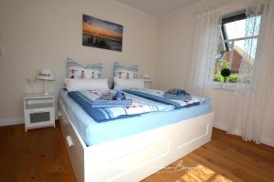 Schlafzimmer mit einem Bett mit blauer Bettwäsche und einem Fenster in der Unterkunft Pension Lütje Huske Zimmer 2 in Südbrookmerland
