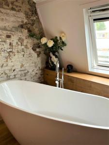 een badkamer met een wit bad en een raam bij Hostellerie Horst in Horst