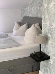 a bed with white pillows and a table with a lamp at Landhaus Ankerplatz im Grünen, strandnah , fernab vom mainstream , ideal für Familien in Gorow