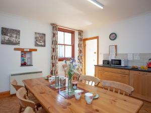 a dining room with a wooden table and a kitchen at The Coach House - Uk35953 in South Pool