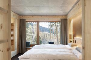 a bedroom with a large bed and a large window at Alpine Lodge Chesa al Parc in Pontresina