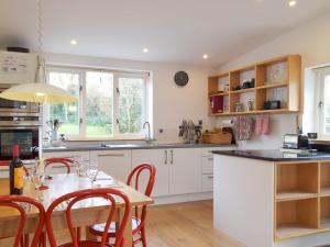 a kitchen with white cabinets and a table with chairs at Collingwood Cottage in Marloes