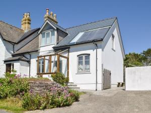 a white house with solar panels on the roof at Collingwood Cottage in Marloes