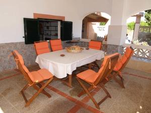 a dining room with a white table and orange chairs at Villa L&oacute;pez in Santanyi