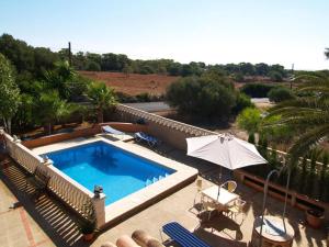 a swimming pool with chairs and an umbrella on a patio at Villa López in Santanyi