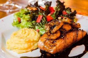 a plate of food with meat and potatoes and a salad at Solar Mirador Exclusive Resort e SPA in Praia do Rosa