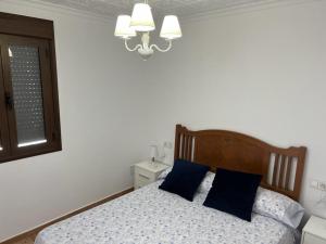 a bedroom with a bed with blue pillows and a chandelier at Agradable casa familiar en Pliego. in Pliego