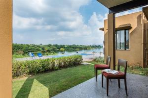 a patio with two chairs and a view of a river at SaffronStays Rose Vineyard by the Lake, Nashik in Nashik
