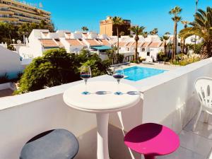 a white table with two glasses of wine on a balcony at Beach Bungalow Holiday Home in Adeje