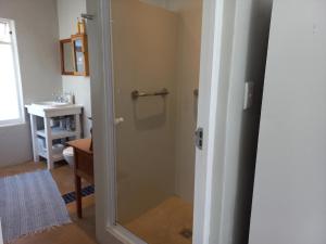 a bathroom with a shower with a glass door at Onrus Garden Cottage, Sunny and Spacious in Hermanus +9 photos