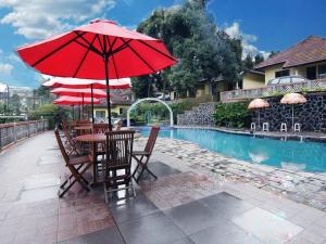 a table and chairs with umbrellas next to a pool at Lembah Ciater Resort Managed by Sahid in Ciater