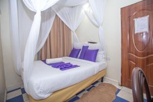 a bedroom with a canopy bed with purple pillows at Happy Springs Hotel & Accomodation in Kericho