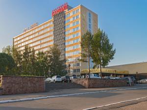 un edificio alto con coches estacionados en un estacionamiento en Hotel Barnaul, en Barnaul