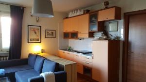 a living room with a blue couch and a kitchen at The Panoramico in Sauze dʼOulx