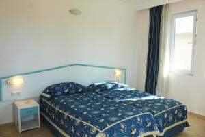 um quarto com uma cama com um edredão azul e uma janela em Belle Ocean Apart Otel em Alanya