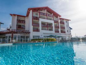 un hotel con piscina di fronte a un edificio di Résidence Mer & Golf Sokoburu a Hendaye