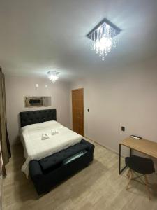 a bedroom with a bed and a table and a chandelier at Pousada Leitzke in Piratini