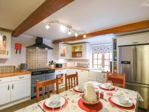 a kitchen with a table and chairs and a refrigerator at Barley Cottage in Axminster