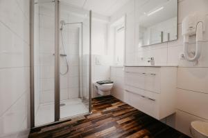 La salle de bains blanche est pourvue d'une douche et de toilettes. dans l'établissement Appartementen Renesse, à Renesse