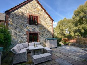 eine Terrasse mit Tisch und Stühlen und ein Gebäude in der Unterkunft Barley Cottage in Axminster