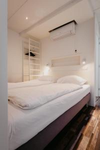 Cette chambre comprend un grand lit blanc et une fenêtre. dans l'établissement Appartementen Renesse, à Renesse