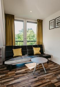 ein Wohnzimmer mit einem schwarzen Sofa und einem Tisch in der Unterkunft Appartementen Renesse in Renesse