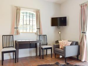 a living room with a desk and a chair and a piano at The Pump House in Kiddemore Green