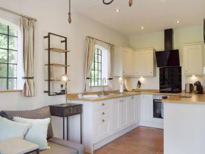 a kitchen with white cabinets and a couch at The Pump House in Kiddemore Green
