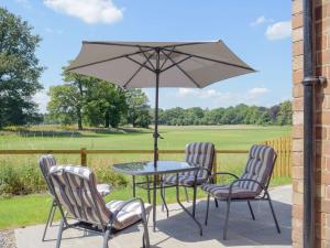 eine Terrasse mit einem Tisch, Stühlen und einem Sonnenschirm in der Unterkunft The Pump House in Kiddemore Green