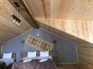 two beds in a room with a wooden ceiling at Hotel Nestt in Stepantsminda