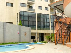 a building with a swimming pool in front of a building at Hotel Hibiscus Louis in Libreville