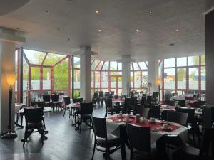 a dining room with tables and chairs and windows at Hotel Mozart in Traunreut