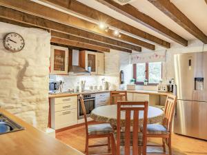 a kitchen with a table and chairs and a clock at Rescorla Cottage in Penwithick