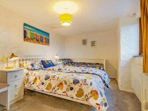 a bedroom with a bed with a colorful comforter at Rescorla Cottage in Penwithick