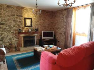 a living room with a red couch and a fireplace at 4 bedrooms villa with private pool enclosed garden and wifi at Empalme de Vilar in Vilar