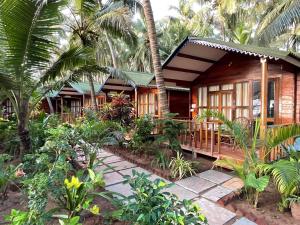 atropical house with a porch and palm trees at Jardim a Mar in Agonda