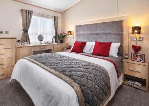 a bedroom with a large bed with red pillows at Golden Sands Holiday Park in Cresswell