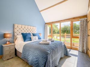 a bedroom with a bed and a large window at The Hovel in Fenny Compton