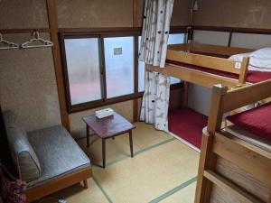 a room with two bunk beds and a table at Guesthouse Tomaru in Takayama