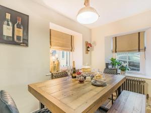 een eetkamer met een houten tafel en 2 ramen bij Keepers Cottage in Durisdeer