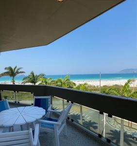 een balkon met een tafel en stoelen en het strand bij Apartamento - CARIBE BRASILEIRO - Praia do Forte - De frente para o mar in Cabo Frio