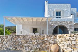 a white house with a stone wall and a fence at Studio with Seaview at Faragas in Angairiá