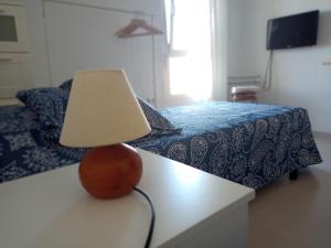 una lámpara sentada en una mesa junto a una cama en Habitación privada económica y acogedora cerca de Cádiz, en Puerto Real