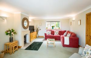 a living room with a red couch and a fireplace at Croft House Sleeps 14 ꕤ Country Views nr Salisbury in Salisbury