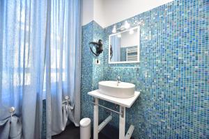 ein blau gefliestes Bad mit einem Waschbecken und einem Spiegel in der Unterkunft Sacconi Palace Suite Roma in Rom