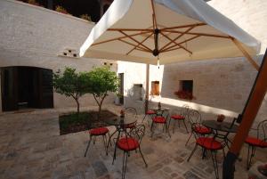 a patio with tables and chairs and an umbrella at La Piccola Corte in Alberobello