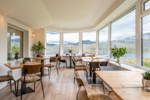 ein Restaurant mit Tischen und Stühlen und großen Fenstern in der Unterkunft Newton Lodge in Unapool