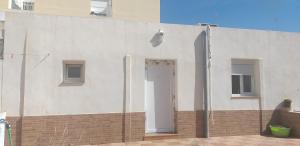 un edificio blanco con una puerta a un lado en C&BLOLA - Habitacion independiente con baño privado y aire acondicionado - Minimo 3 dias en Puerto Real