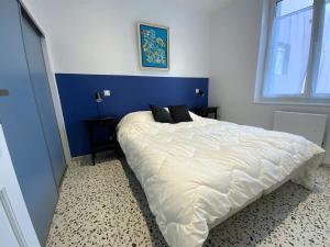 een slaapkamer met een groot wit bed en een blauwe muur bij Les Lutins - sur la plage in Wimereux